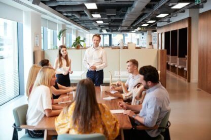 businessman and businesswoman addressing group of young candidates sitting around table e1661423586162