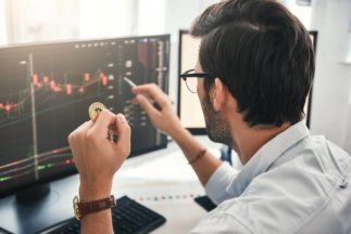 exchange stock market back view of young professional trader in eyeglasses pointing on the data on e1661425319882