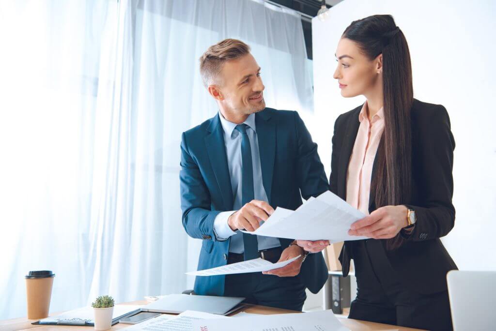 smiling business colleagues doing paperwork at workplace in office