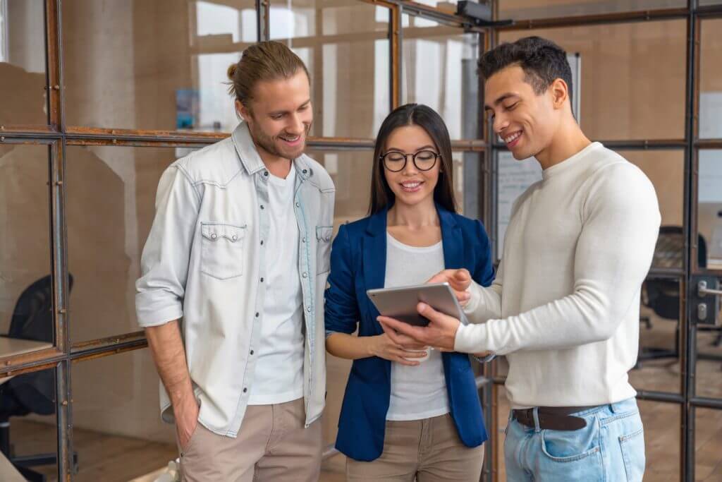 three young business professionals standing together and discussing over business report